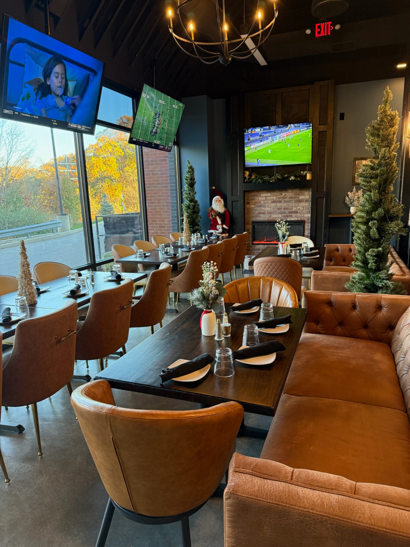 Private event room at Clubhouse Lounge + Kitchen in Edwardsville, Illinois with long wood tables, leather seating, a fireplace, and TVs