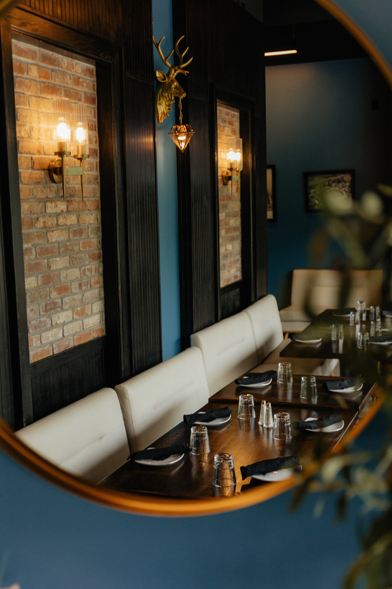 Set table and bench seating in the Clubhouse private event space in Edwardsville, seen in a round mirror on the wall