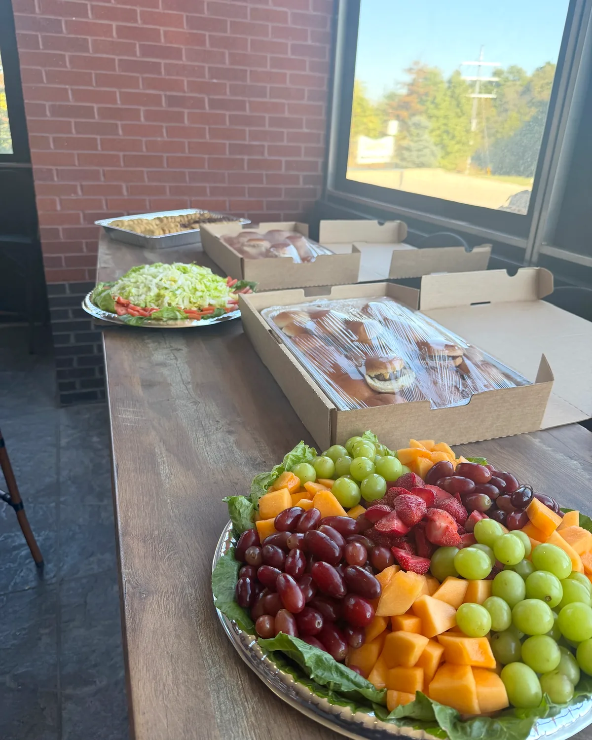 Clubhouse catering spread with fruit platter, salad and sandwich trays