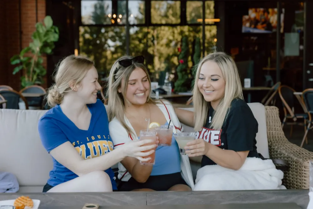 Friends toasting on the covered patio at Clubhouse Lounge + Kitchen